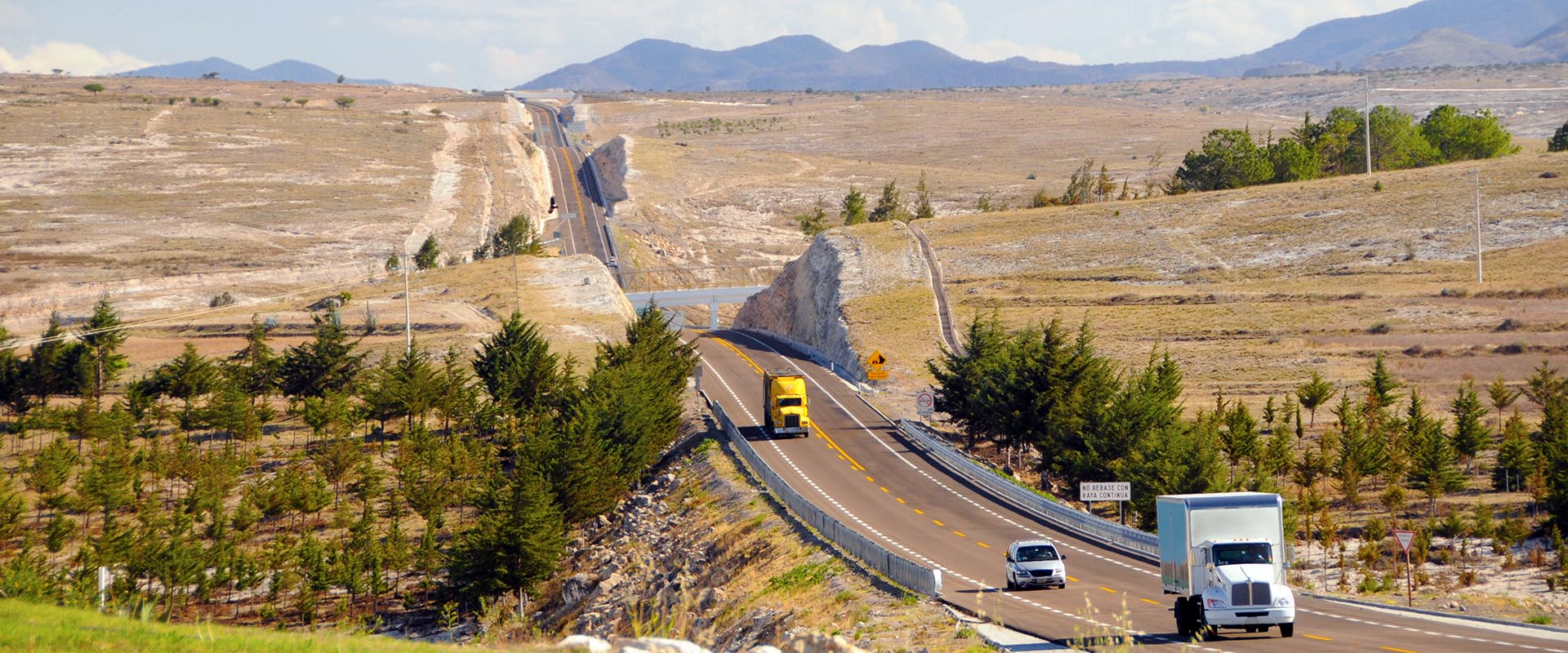 A car and two trucks driving along the highway in Mexico
