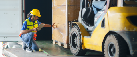 Woman loading pallets onto a forklift.